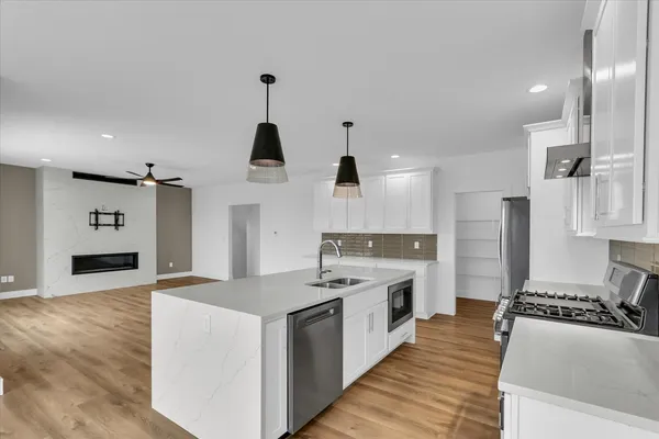 a large kitchen with stainless steel appliances kitchen island a stove a sink dishwasher and a oven with white cabinets