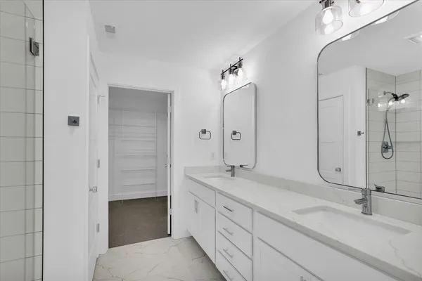 a spacious bathroom with a granite countertop sink a mirror and shower