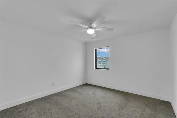 an empty room with a window and ceiling fan