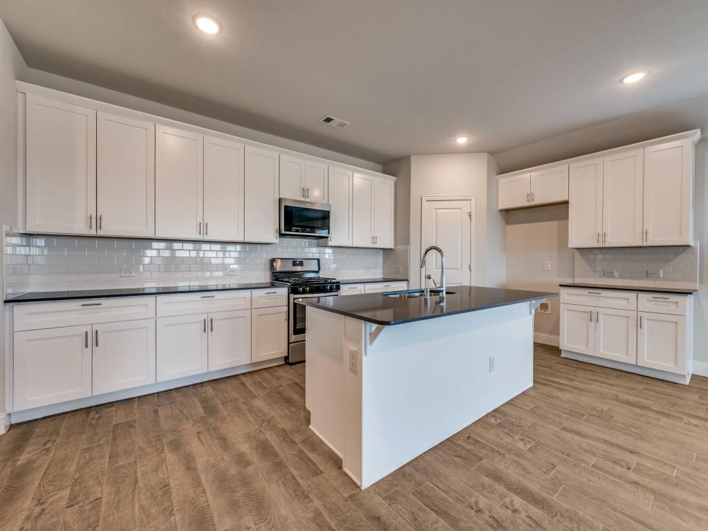 930 Waterview Drive Prosper, TX 75078 - Photo 9 of 17 a kitchen with kitchen island granite countertop white cabinets white stainless steel appliances with a sink and dishwasher