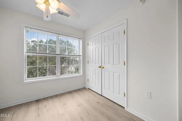 an empty room with wooden floor cabinet and windows