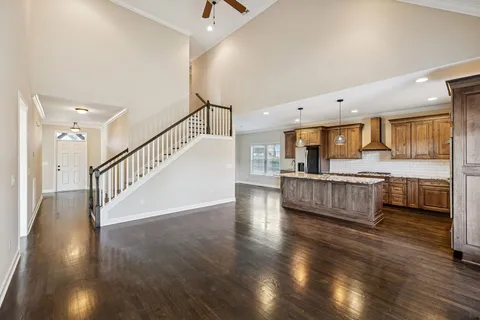 a kitchen with granite countertop a stove a sink wooden floor and cabinets
