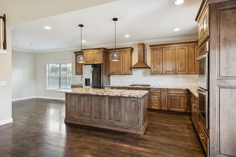 a kitchen with granite countertop a stove a sink and white cabinets with wooden floor