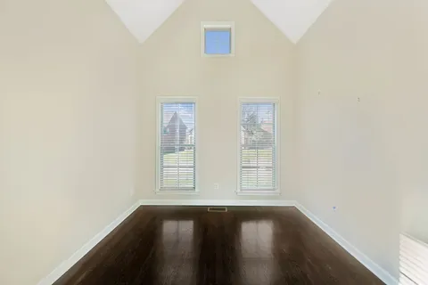 a view of an empty room with wooden floor and windows