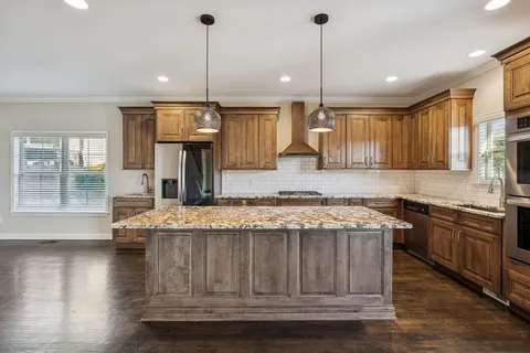 a kitchen with kitchen island granite countertop wooden cabinets and a fireplace