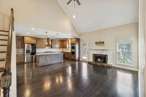 a living room with stainless steel appliances furniture a fireplace and wooden floor