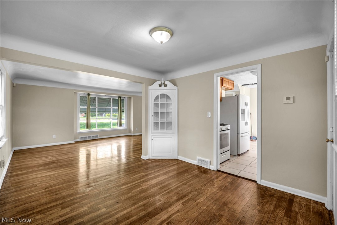 2313 North Taylor Road Cleveland Heights, OH 44112 - Photo 3 of 32 Hardwood flooring extending through the primary living space, featuring a large bay window and a built-in corner cabinet with glass-paneled doors