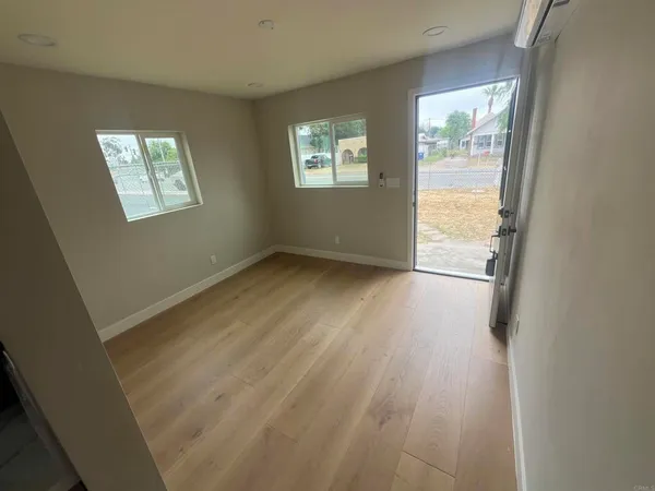 a view of an empty room with wooden floor and a window