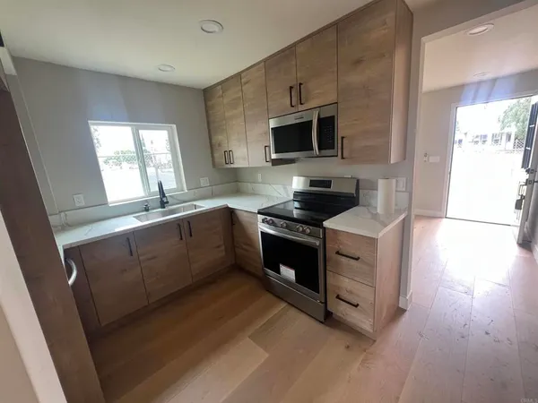 a kitchen with stainless steel appliances a sink dishwasher a microwave oven and a stove with wooden floor