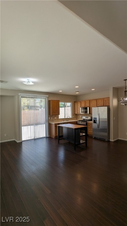 9121 Watermelon Seed Avenue Las Vegas, NV 89143 - Photo 21 of 21 Kitchen with appliances with stainless steel finishes, brown cabinets, open floor plan, decorative backsplash, and a breakfast bar area