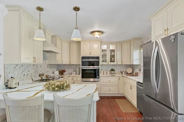 a kitchen with stainless steel appliances granite countertop a sink a stove a refrigerator cabinets and chairs
