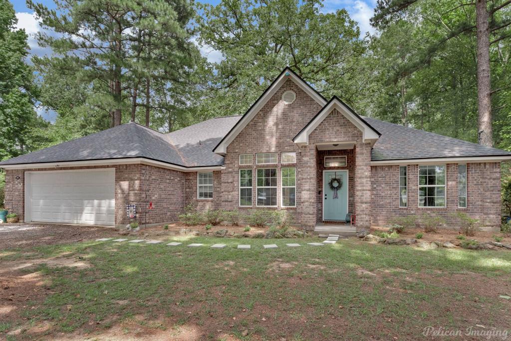 Ranch-style home with brick siding, an attached garage, a shingled roof, driveway, and a front lawn