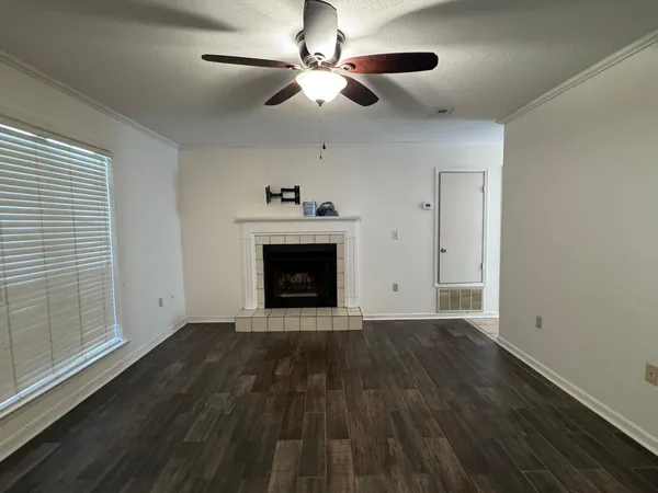 a view of an empty room with wooden floor a ceiling fan and a window