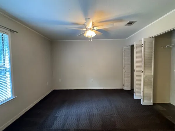 an empty room with wooden floor closet fan and windows