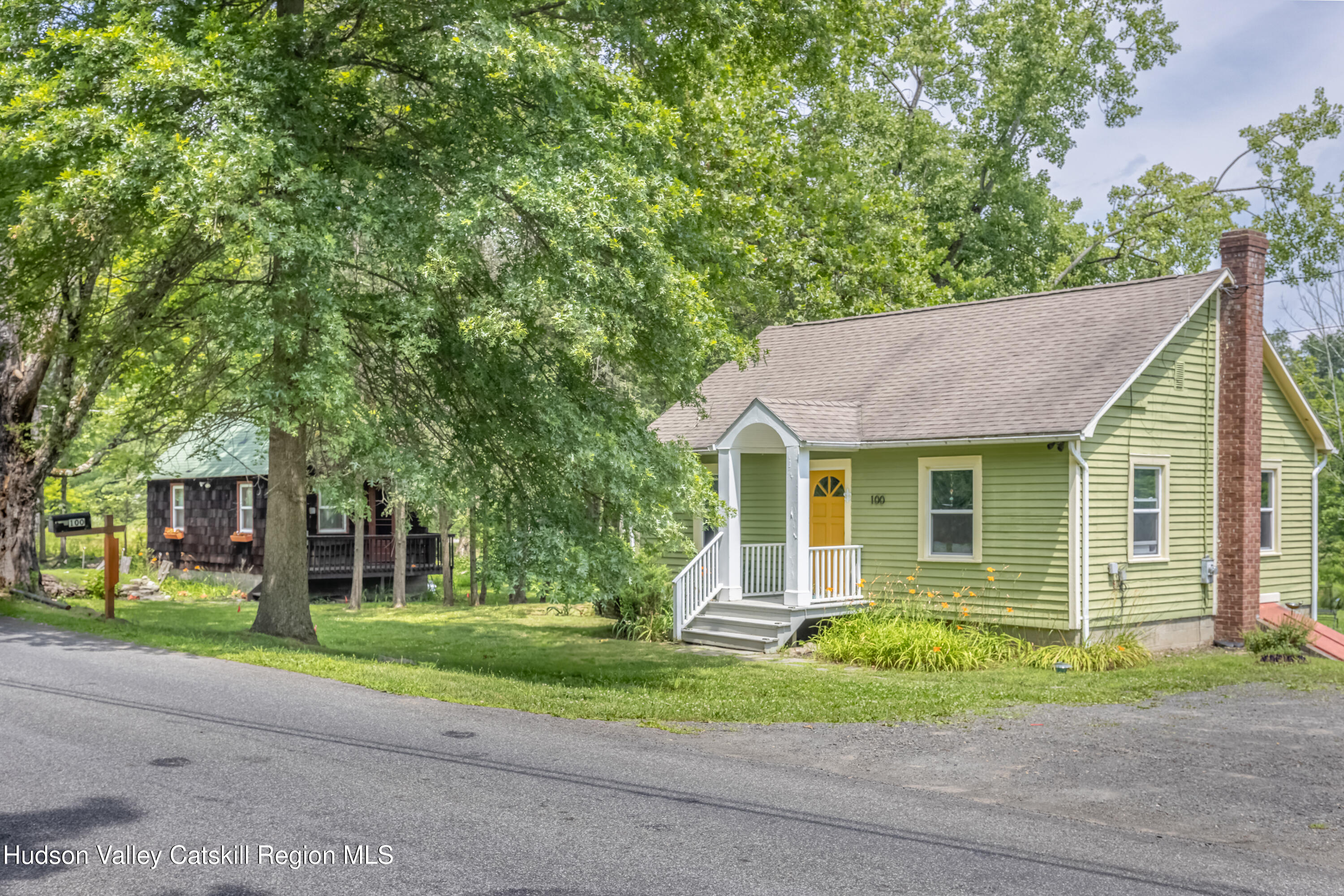 a view of a house with a yard plants and large tree
