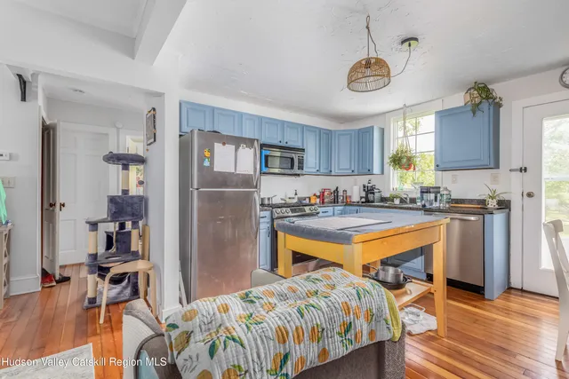 a kitchen with stainless steel appliances granite countertop a refrigerator a stove top oven a sink dishwasher and a dining table with wooden floor
