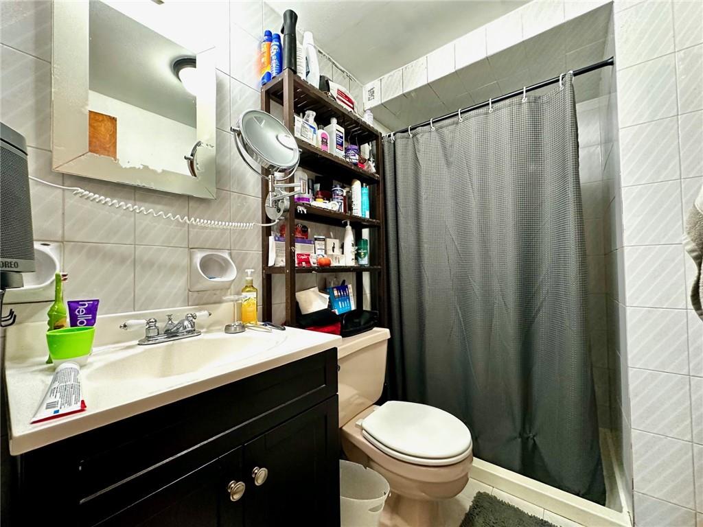 1453 85th Street Brooklyn, NY 11228 - Photo 11 of 18 a bathroom with a sink a toilet and shower curtain