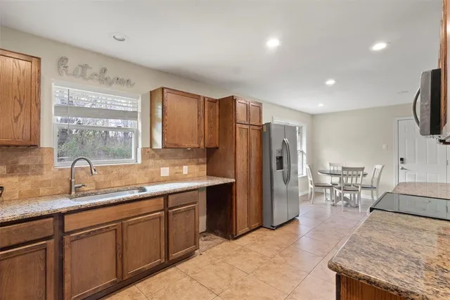 a kitchen with stainless steel appliances granite countertop a sink refrigerator and cabinets