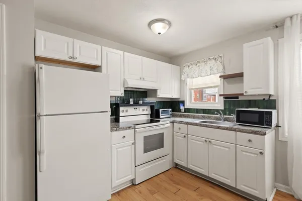 a kitchen with white cabinets and white appliances