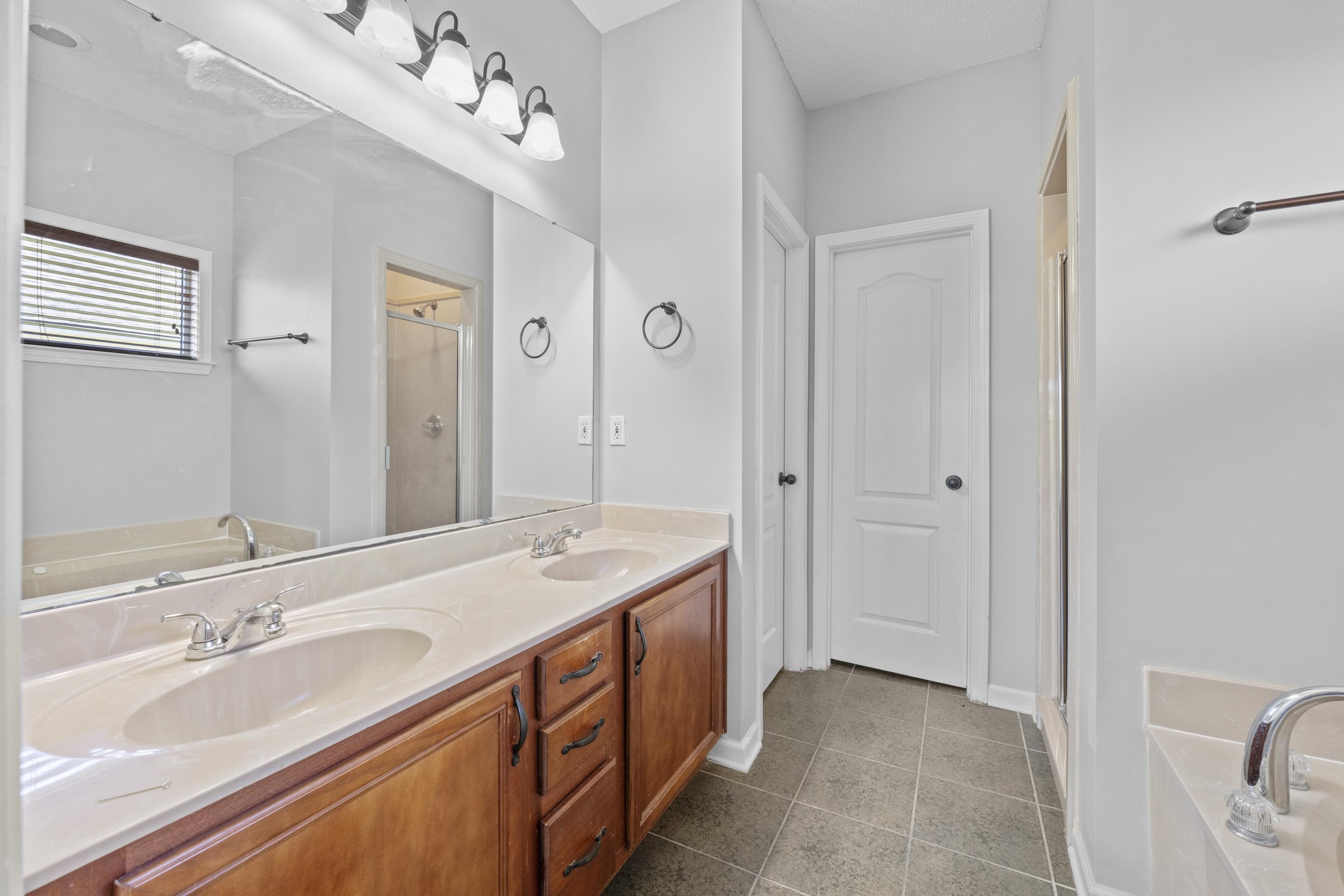 50 Abbey Road Oakland, TN 38060 - Photo 16 of 26 Double vanity with integrated sinks, wood-finish cabinetry, and a large mirror with overhead lighting