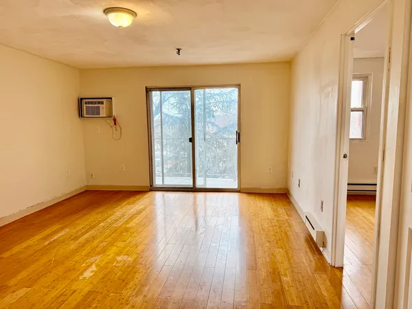 a view of an empty room with wooden floor and a window