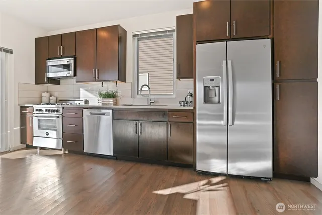 a kitchen with stainless steel appliances granite countertop a refrigerator a sink a stove and oven