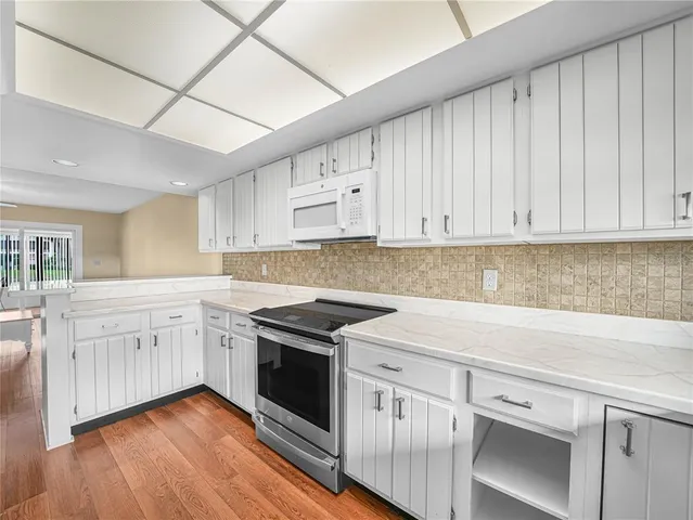 a kitchen with granite countertop white cabinets and white appliances