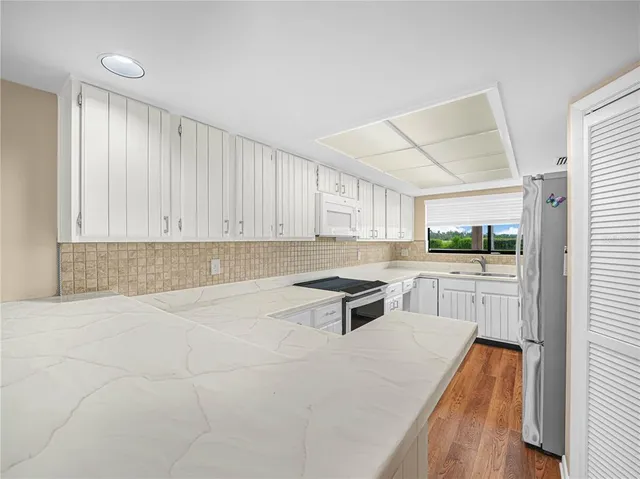 a kitchen with granite countertop a stove a sink and a refrigerator