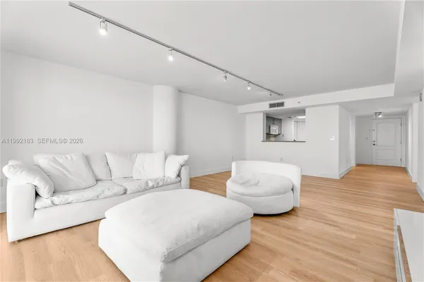 a living room with couches and white walls with wooden floor