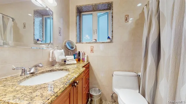 a bathroom with a granite countertop sink mirror vanity and toilet