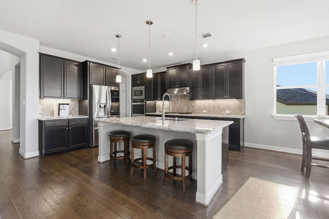 15604 Cabrillo Way Austin, TX 78738 - Photo 3 of 33 a kitchen with kitchen island granite countertop a sink cabinets and wooden floor
