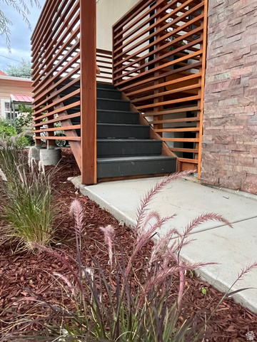302 North Harrisville Road Ogden, UT 84404 - Photo 9 of 11 Exterior staircase with wood slat railings, stone veneer wall, and landscaped planting area