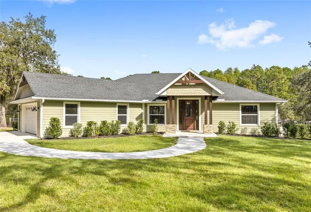 a front view of a house with a garden and trees