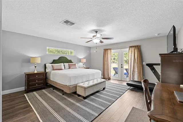 a spacious bedroom with a bed and a flat tv screen on dresser