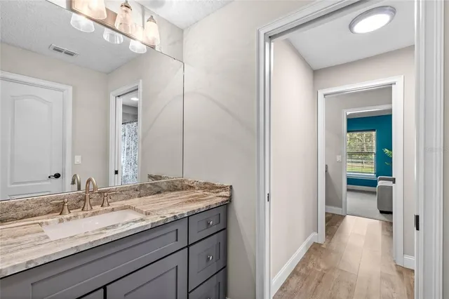 a en suite bathroom with a granite countertop sink and a mirror