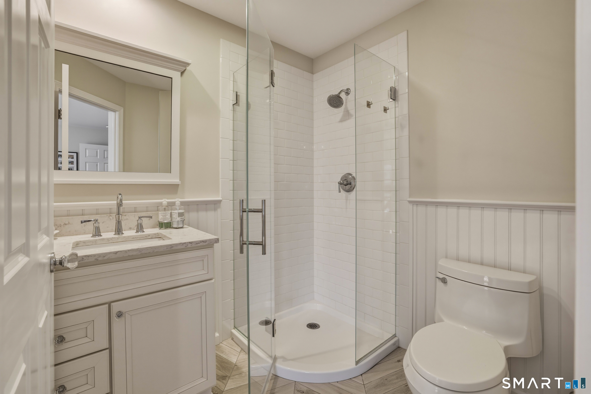 7 Timber Lane Guilford, CT 06437 - Photo 18 of 40 a bathroom with a toilet a sink a glass door a shower a mirror and vanity