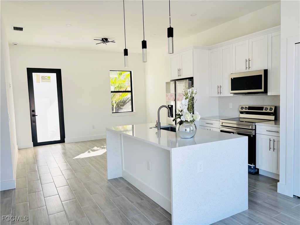 3010 45th Street Southwest Lehigh Acres, FL 33976 - Photo 11 of 29 a kitchen with stainless steel appliances a sink a stove and a refrigerator