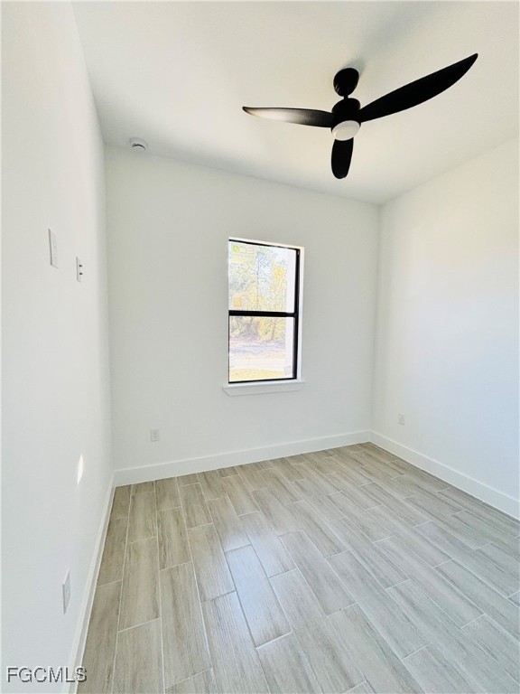 3010 45th Street Southwest Lehigh Acres, FL 33976 - Photo 18 of 29 an empty room with wooden floor chandelier fan and windows