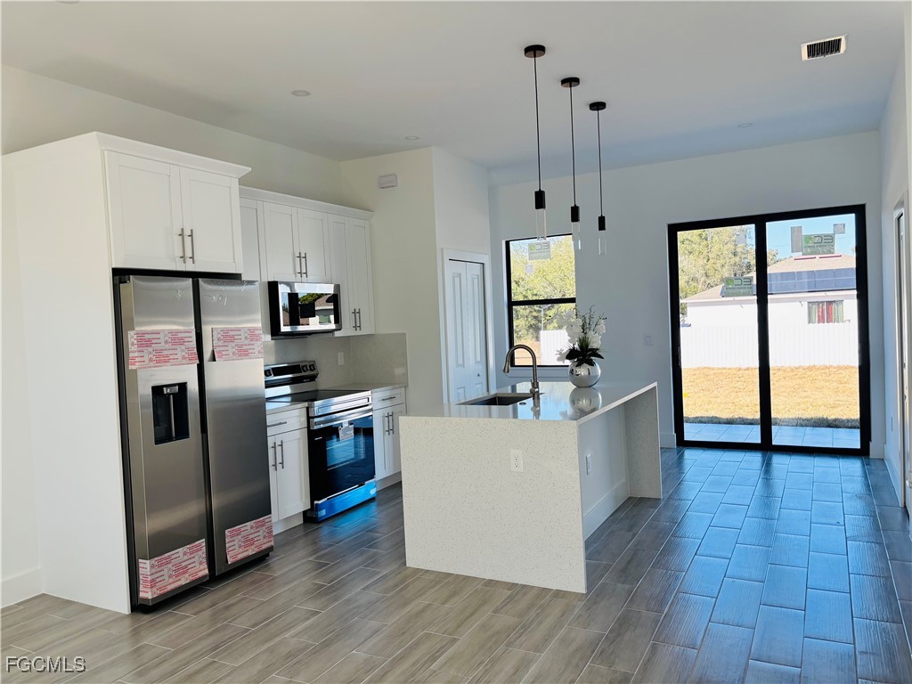 3010 45th Street Southwest Lehigh Acres, FL 33976 - Photo 6 of 29 a kitchen with stainless steel appliances a refrigerator and a stove top oven