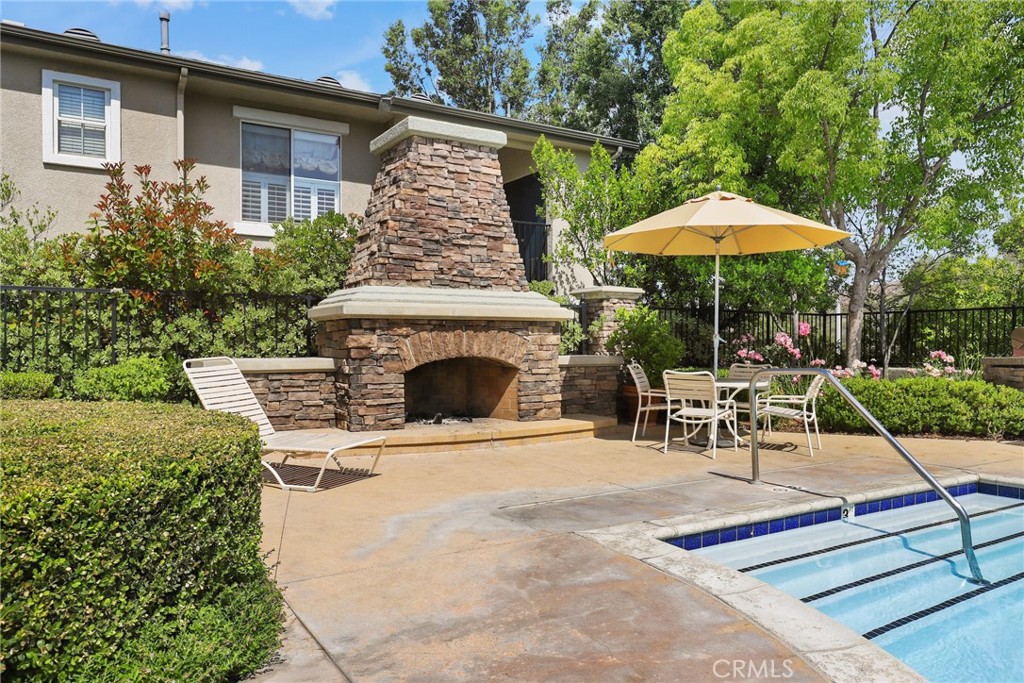 20000 Plum Canyon Road, Unit 221 Saugus, CA 91350 - Photo 24 of 30 a view of a backyard with table and chairs under an umbrella
