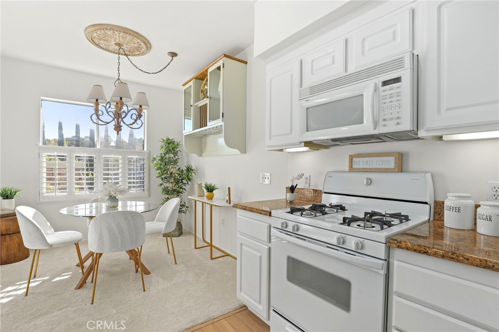 20000 Plum Canyon Road, Unit 221 Saugus, CA 91350 - Photo 8 of 30 a kitchen with granite countertop a stove a dining table and chairs