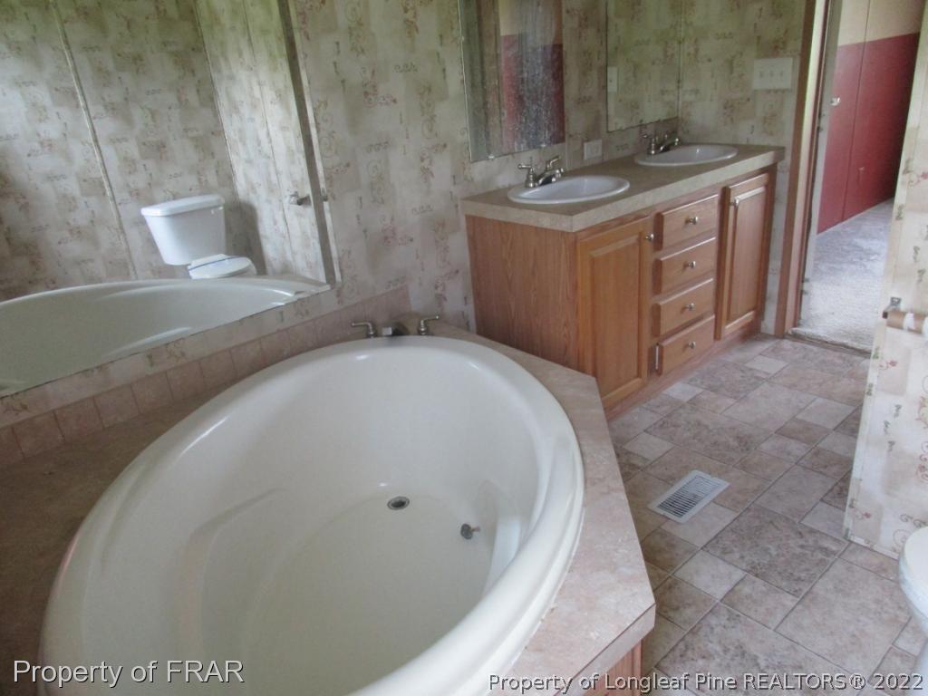 794 Wiggins Road Clinton, NC 28328 - Photo 16 of 18 a bathroom with a granite countertop sink and a mirror