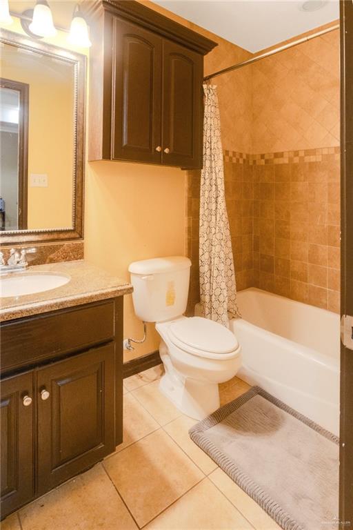 22811 Skinner Road Edcouch, TX 78538 - Photo 25 of 38 Tiled bathroom featuring a built-in tub, vanity with a stone-finish countertop, and dark wood-finish cabinetry