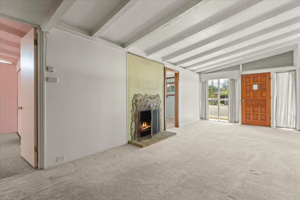 a view of an empty room with a fireplace and a window