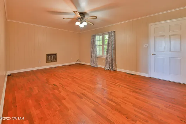 an empty room with wooden floor fan and windows