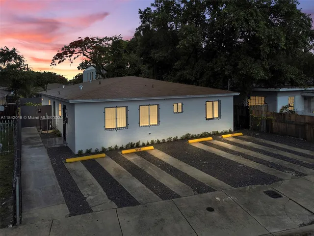 a front view of a house with yard and trees around