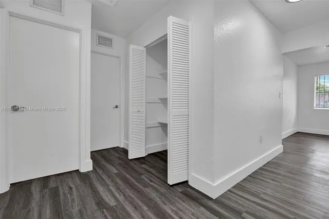 a view of a room with wooden floor and white walls