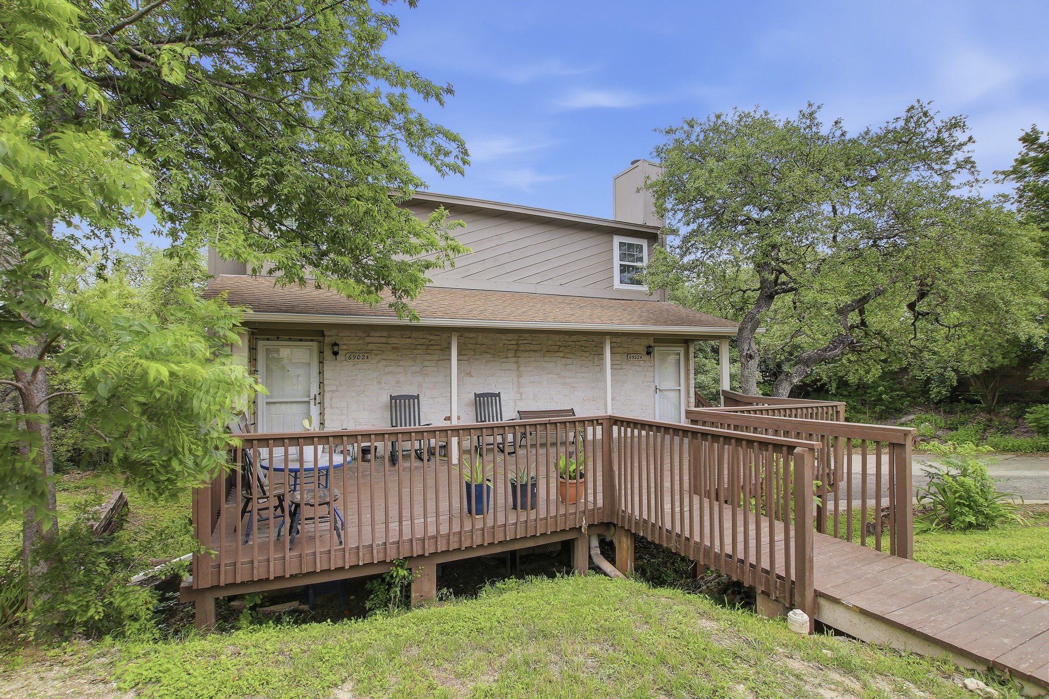 6902 Rifle Bend Austin, TX 78736 - Photo 3 of 33 a view of a wooden house with a wooden deck and backyard