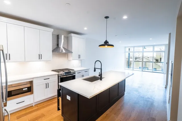 a kitchen with a stove a sink a refrigerator and wooden floor