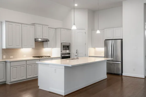 a kitchen with stainless steel appliances a sink a stove a refrigerator and cabinets
